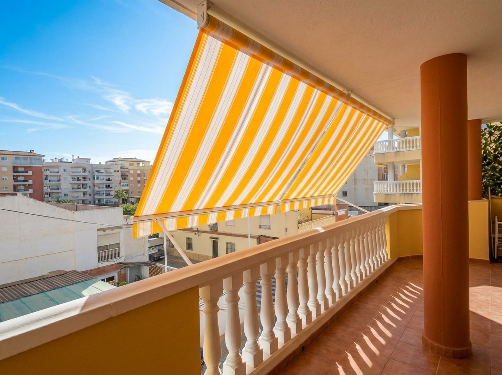 Terraza del piso con toldo a rayas, barandilla y vistas desde la segunda planta