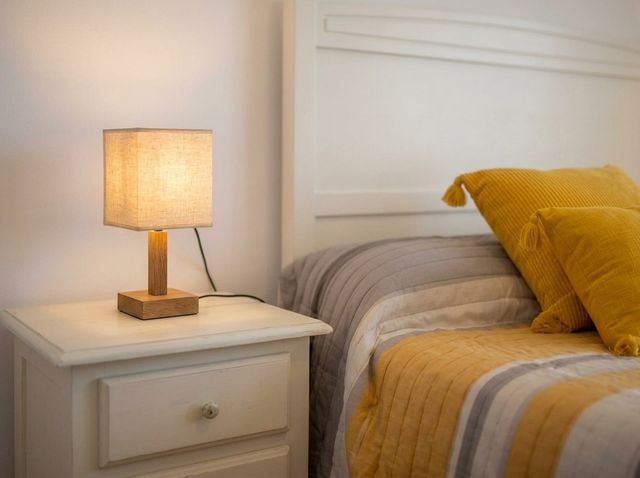 Cama con cabecero blanco y mesita