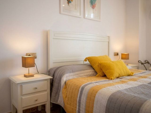 Dormitorio con cabecero blanco y colcha