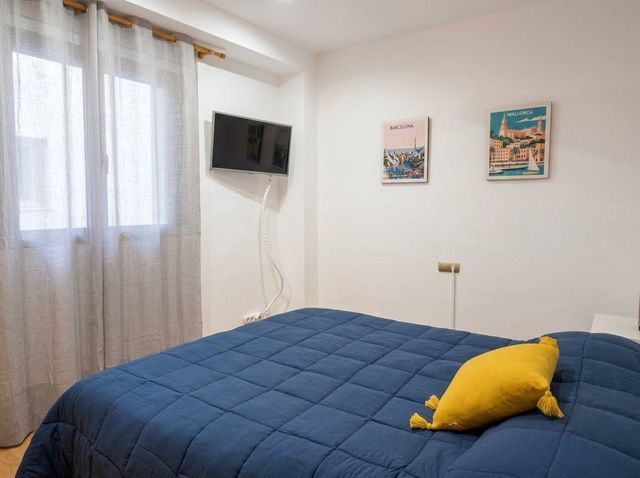 Dormitorio con colcha azul y ventana