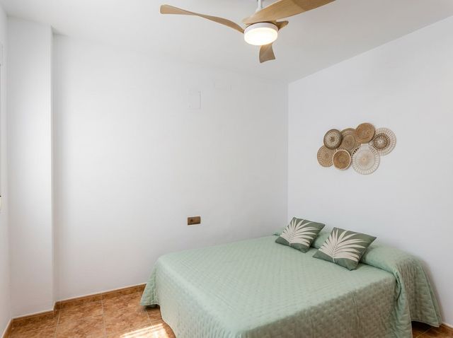 Dormitorio con cama y ventilador de techo